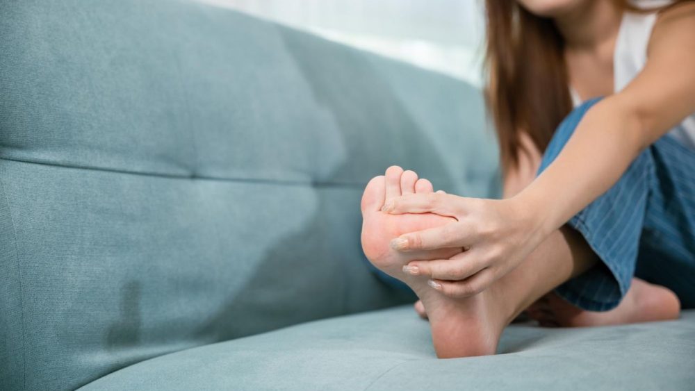 oman-sitting-sofa-holding-her-feet-stretch-muscles-have-symptoms