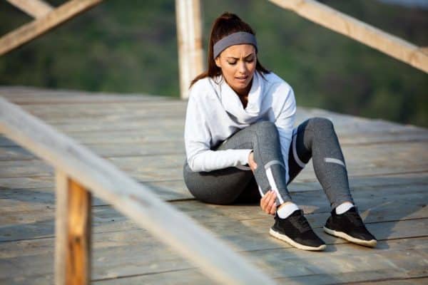 young-sportswoman-experiencing-pain-her-leg-while-having-sports-training-nature